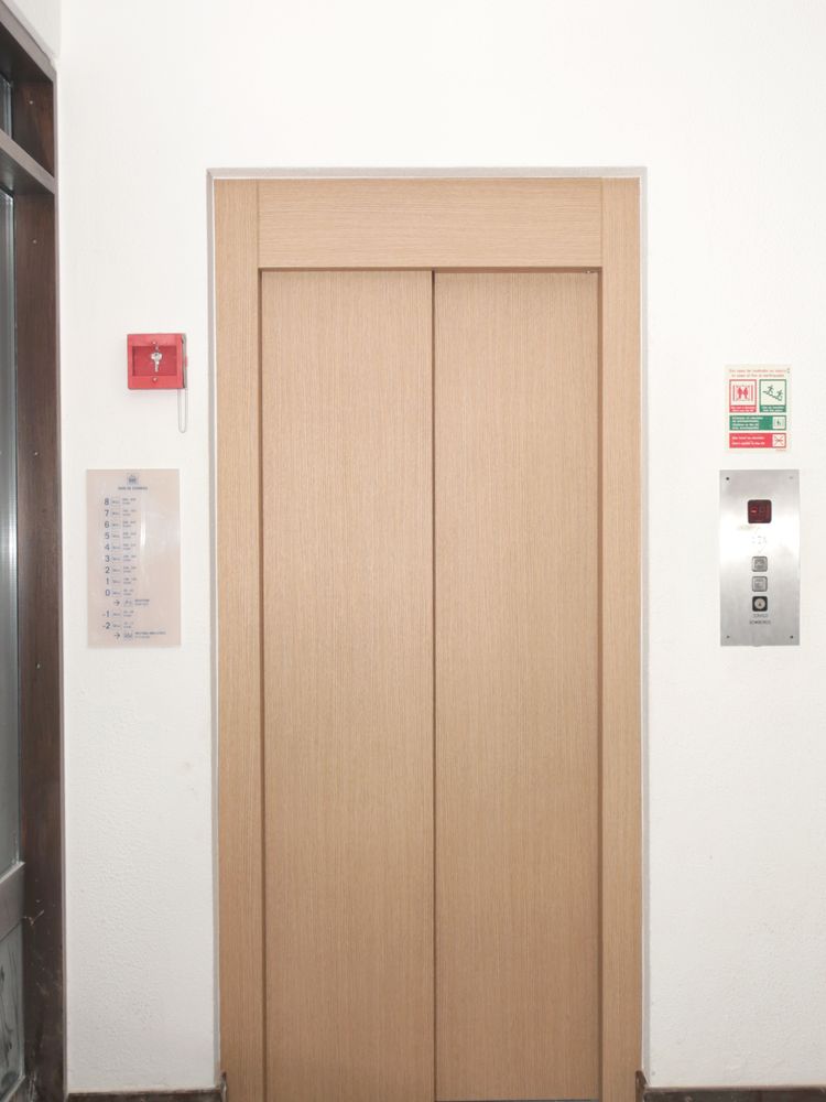 La même porte d’ascenseur habillée d’un film effet bois clair après covering